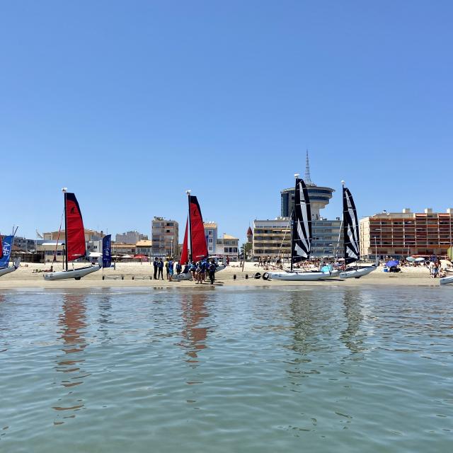 Bateaux à voile sur la plage avec les immeubles et le Phare de la Méditerranée en fond